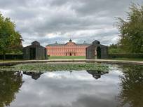 Auf dem Foto ist das Schloss von Rastatt zu sehen. Davor liegt ein großer Teich sowie eine Parkanlage.